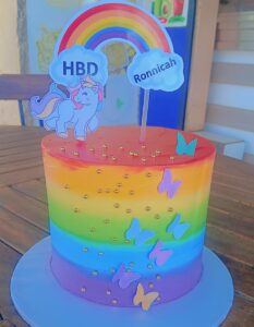 "Vibrant six-layer rainbow cake with buttercream frosting, perfect for birthdays in Nairobi"